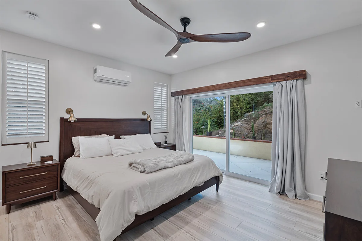 Bedroom with a wood bed frame, white bedding and sliding doors to the terrace