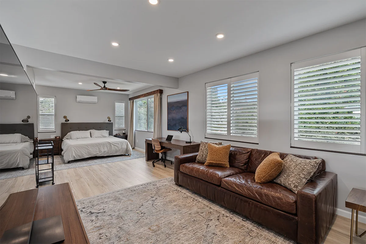 Spacious bedroom suite with a leather sofa, a desk and white bedding